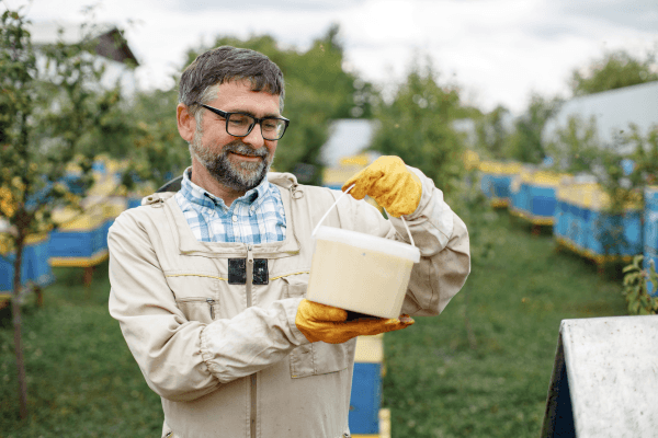 A beekeeper with a honey bucket