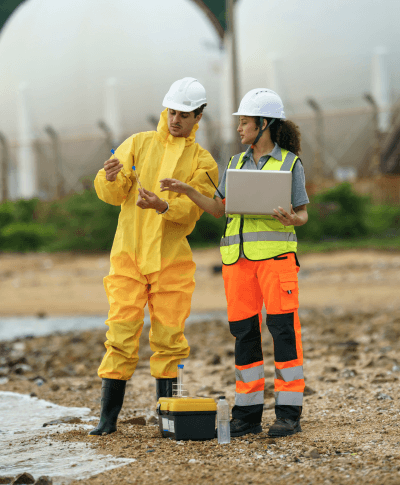 A man and woman in hard hats doing test tube soil analysis in a field